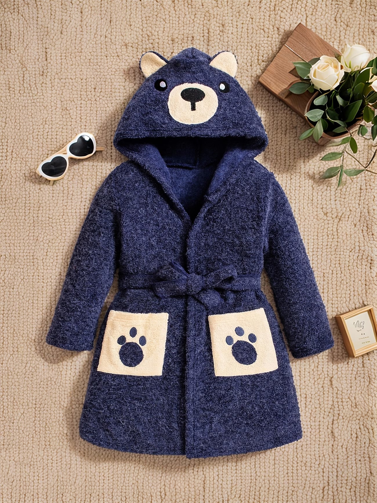 Blue children's robe with bear design on a beige surface