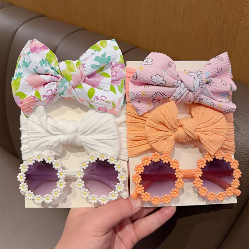 Set of colorful hair bows and decorative sunglasses held by a hand.